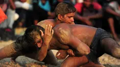 Pegulat melakukan gerakan kuncian saat mengikuti kompetisi gulat tradisional India yang diadakan di desa Rampur, India (7/10). Olahraga tradisional ini terus di lestarikan sebagai bagian dari budaya India. (AFP Photo/Sanjay Kanojia)