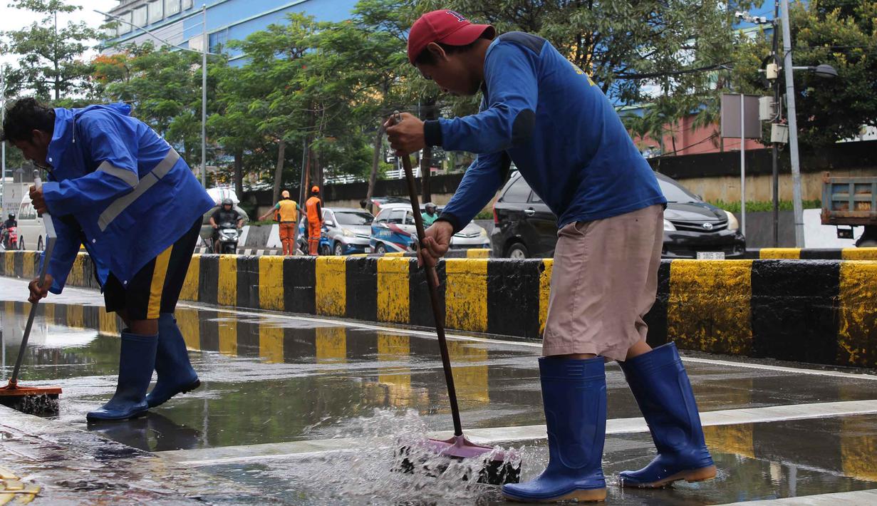 Penanganan dilakukan bersama di lokasi untuk memulihkan kondisi jalan agar kembali aman dan dapat dilalui masyarakat. Tampak dalam foto, petugas Dinas Sumber Daya Air (SDA) DKI Jakarta membersihkan sisa lumpur di Jalan Gunung Sahari Raya atau tepat di depan Mangga Dua Square, Jakarta, Selasa (13/1/2026). (merdeka.com/magang/Rendi Saputra)
