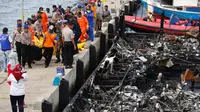 Petugas kepolisian bersama Tim SAR gabungan mengevakuasi kantong jenazah korban kapal Zahro Express yang terbakar, di Pelabuhan Muara Angke, Minggu (1/1). Sejumlah jenazah ditemukan dengan kondisi hangus terbakar dari kapal. (REUTERS/Darren Whiteside)
