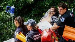 Petugas mengevakuasi seorang pemuda yang terluka parah setelah menjadi korban ledakan di Central Park, New York, Minggu (3/7). Sebagian Central Park pun langsung ditutup sementara personel NYPD melakukan penyelidikan. (Kena Betancur/AFP)
