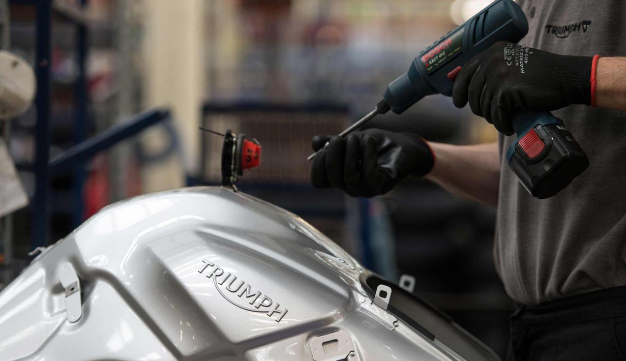 Pekerja mengencangkan baut sepeda motor Triumph di pabriknya di Hinckley, Inggris (2/10). Awalnya Triumph dibentuk sebagai perusahaan manufaktur sepeda di Coventry pada tahun 1887. (AFP Photo/Oli Scarff)