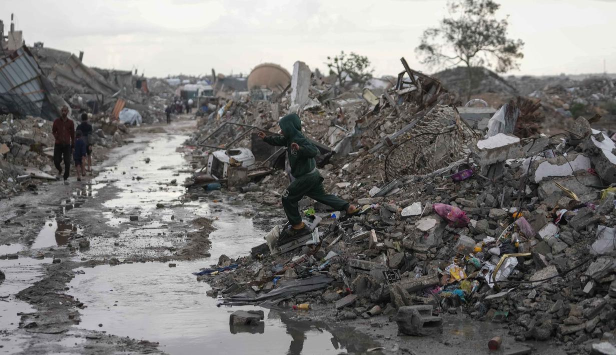 Sumur-sumur air juga mengalami kerusakan, menyebabkan pasokan air menjadi langka. Tampak dalam foto, seorang anak Palestina berjalan di bawah hujan di kawasan Sheikh Radwan, Kota Gaza, pada Jumat 14 November 2025. (AP Photo/Jehad Alshrafi)