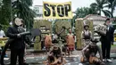 Mereka menilai proyek ini sebagai solusi palsu yang mengancam hutan alam dan ruang hidup masyarakat adat demi ambisi bioetanol. Tampak dalam foto, aktivis Greenpeace Indonesia bersama beberapa pemuda Papua menggelar aksi teatrikal saat berunjuk rasa di depan Kantor Kementerian Koordinator bidang Perekonomian, Jakarta, Kamis (18/12/2025). (Yasuyoshi Chiba/AFP)