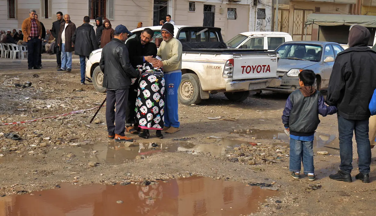 Warga menenangkan wanita usai serangan bom mobil ganda di Kota Benghazi, Libya, Rabu (24/1). Korban tewas di antaranya pemimpin unit investigasi dan penangkapan yang bertugas untuk Komando Pasukan Keamanan Libya Timur. (AFP PHOTO/Abdullah DOMA)
