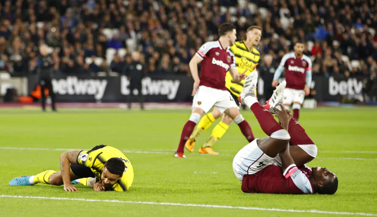 Pemain West Ham United Kurt Zouma (kanan) memegang pergelangan kakinya setelah berebut bola saat melawan Watford pada pertandingan sepak bola Liga Inggris di Stadion London, London, Inggris, 8 Februari 2022. West Ham United menang 1-0. (AP Photo/David Cliff)