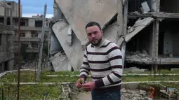 Mohamed Ataya atau yang dikenal sebagai "Abu Maher" menanam tanaman di atap sebuah gedung yang rusak di Ghouta, pinggiran Damaskus, Suriah (3/3). (AFP/Amer Almohibany)