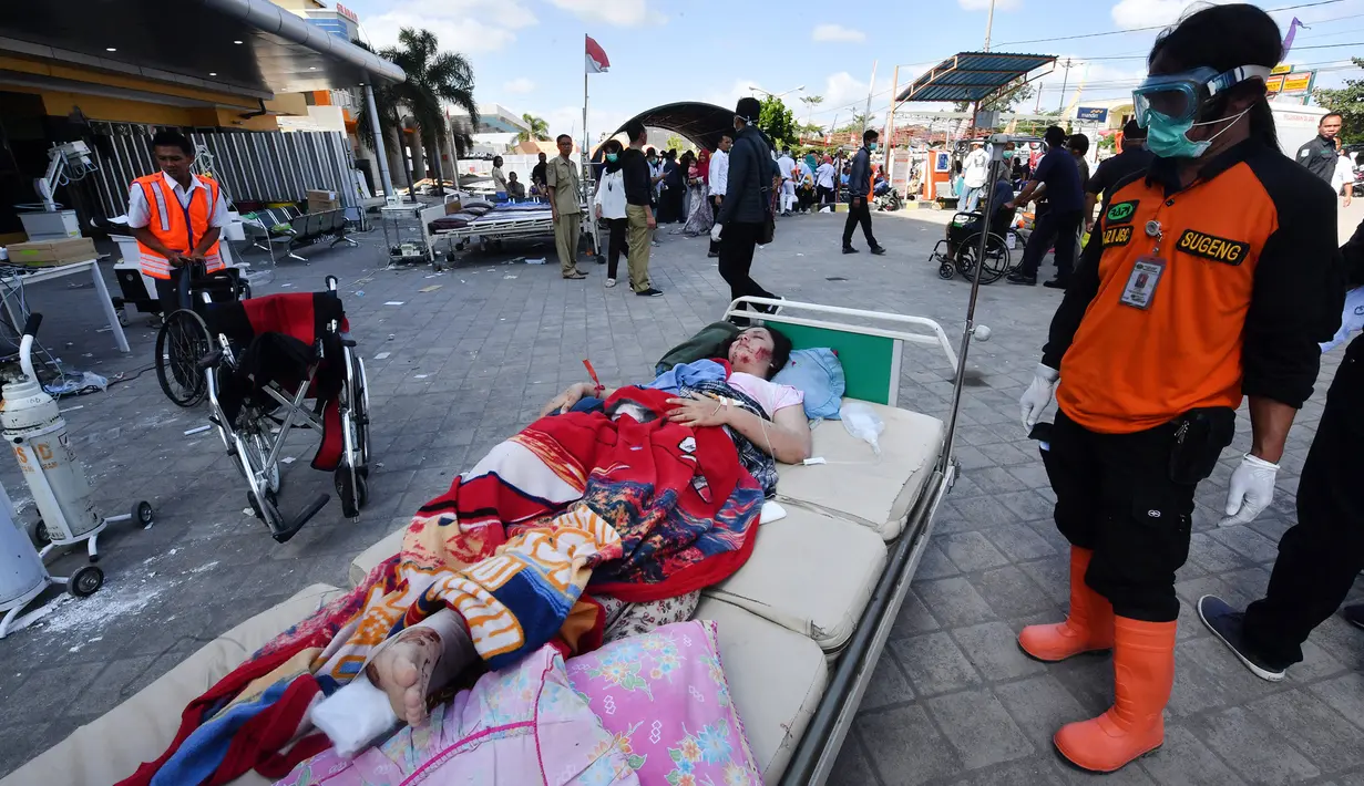 Korban gempa Lombok yang terluka menunggu bantuan medis di luar Rumah sakit Moh. Ruslan di Mataram, Senin (6/8). Aparat gabungan terus melakukan evakuasi dan penanganan darurat akibat bencana gempa bermagnitudo 7 yang mengguncang Lombok. (AFP/ADEK BERRY)