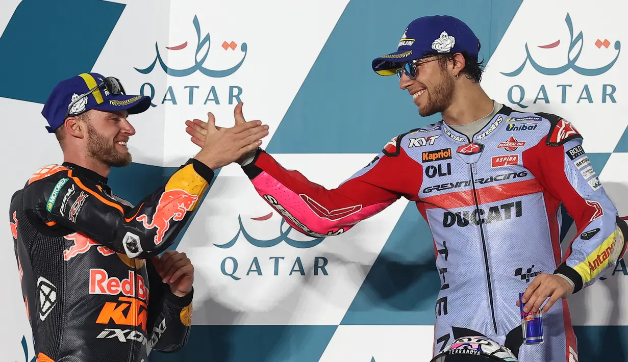 Pembalap tim Gresini Racing Enea Bastianini (kanan) yang menempati tempat pertama mengucapkan selamat kepada pembalap tim Red Bull KTM Factory Racing Brad Binder di podium setelah balapan perdana MotoGP 2022 seri Qatar GP di Sirkuit Internasional Lusail, Minggu (6/3/2022). (KARIM JAAFAR/AFP)