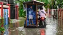 Ketinggian air bervariasi, dan di beberapa lokasi, warga terpaksa harus menembus banjir dengan sepeda motor mereka. Tampak dalam foto, seorang pria bersama seorang anak melewati banjir di jalan yang tergenang setelah hujan deras di permukiman Darul Imarah, pinggiran Banda Aceh, pada Kamis 27 November 2025. (CHAIDEER MAHYUDDIN/AFP)