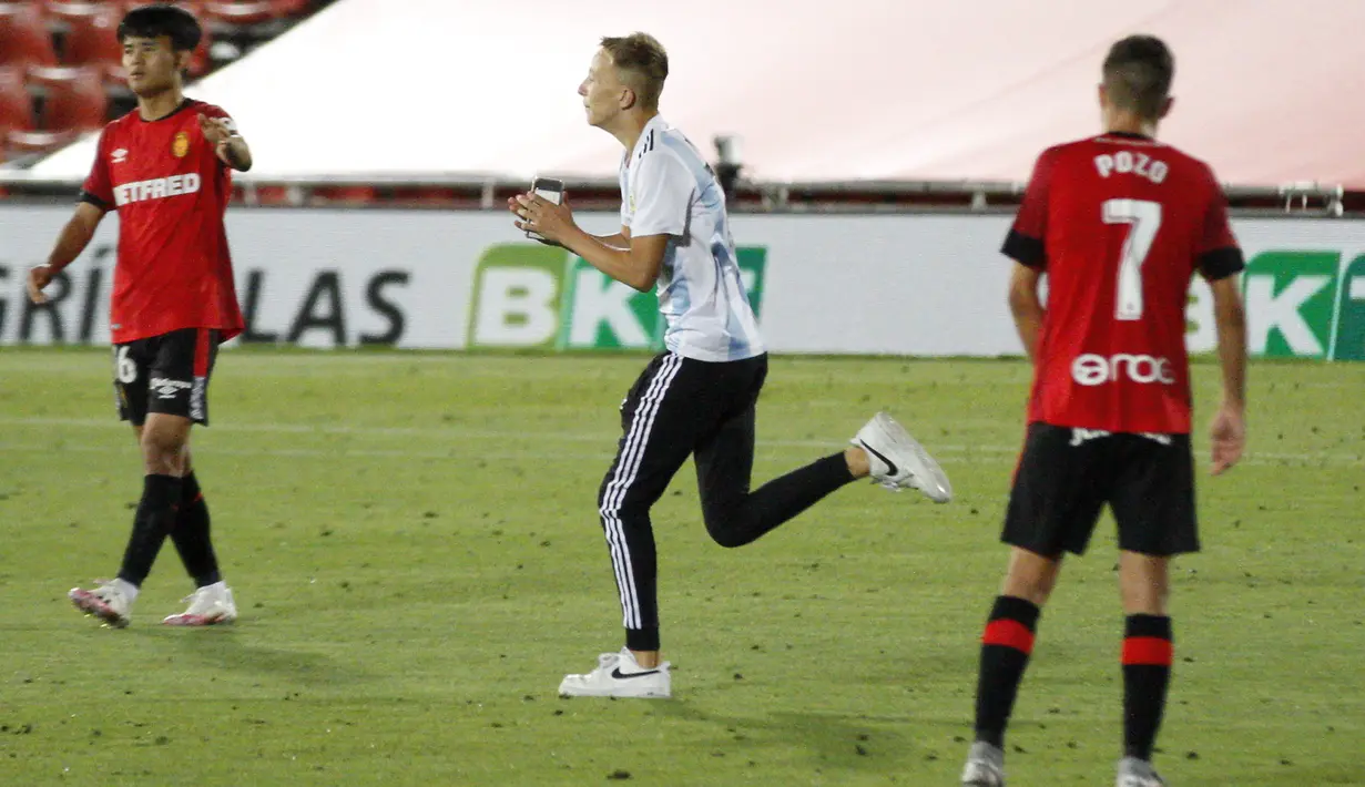 Seorang penyusup (tengah) masuk ke lapangan saat pertandingan La Liga antara Mallorca dengan FC Barcelona di Son Moix Stadium, Palma de Mallorca, Spanyol, Sabtu (13/6/2020). Dalam pertandingan tersebut Barcelona mengalahkan Mallorca dengan skor 4-0. (AP Photo/Francisco Ubilla)