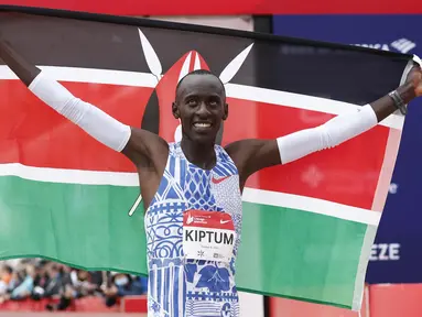 Pelari Kenya, Kelvin Kiptum melakukan selebrasi dengan membentangkan bendera negaranya setelah memenangkan Chicago Marathon 2023 di Chicago, Illinois, Amerika Serikat, 8 Oktober 2023. Ia memecahkan rekor sebagai pelari marathon tercepat di dunia dengan mencatatkan waktu 2 jam 35 detik. (AFP/Kamil Krzaczynski)