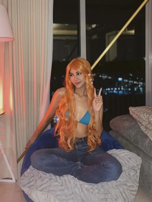 Anya Geraldine tampil sebagai Nami, ia mengenakan atasan bikini biru dipadukan celana denim. Lengkap dengan wig orange panjang dan hairclipnya. (@anyageraldine)