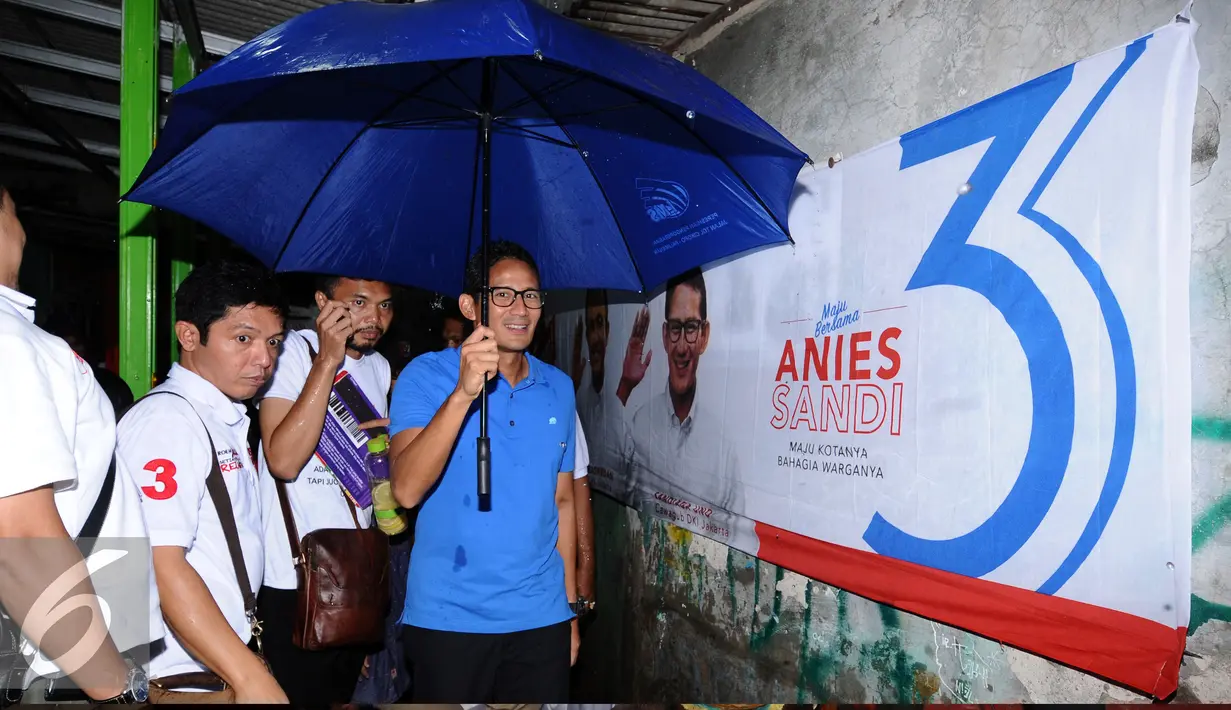 Calon Wakil Gubernur DKI Jakarta, Sandiaga S Uno (kanan) berpayung menyusuri lorong gang Jalan Tanjung Barat Selatan, Jakarta, Minggu (20/11). Sandiaga melantik relawan komunitas Anies-Sandi tingkat RW Lenteng Agung. (Liputan6.com/Helmi Fithriansyah)