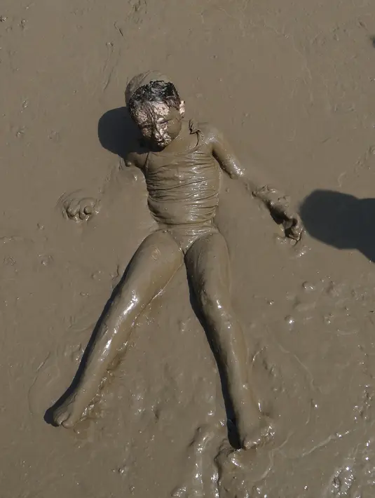 Lilly Fielauer berendam dalam dalam kubangan berisi lumpur saat perayaan Mud Day atau Hari Lumpur Tahunan di Westland, Michigan, AS, Selasa (10/7). Dalam Mud Day kali ini para pesertanya yang ikut adalah anak-anak.  (AP/Carlos Osorio)