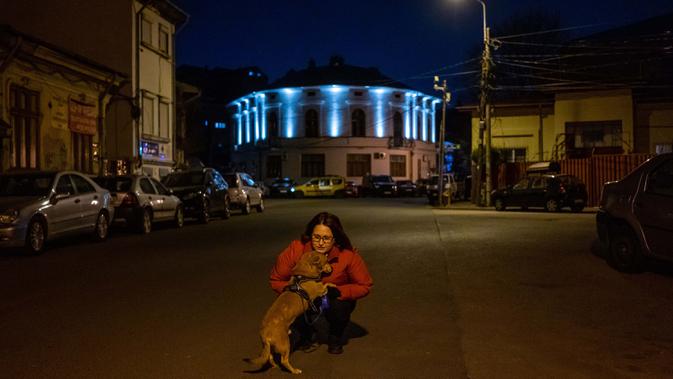 Agnes Nicolaesu (43) berpose dengan anjingnya Boby (13) di Bucharest (27/3/2020). Undang-undang militer, yang disahkan pemerintah Rumania untuk mengurangi penyebaran virus corona, menyatakan berjalan bersama anjing adalah salah satu  kegiatan yang masih diizinkan. (AFP/Andrei Pungovschi)