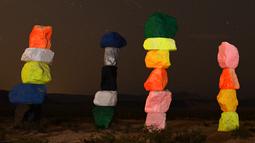 Meteor Perseid melintasi langit di atas instalasi seni "Seven Magic Mountains" dekat Jean, Nevada (13/8). Instalasi seni Seven Magic Mountains ini dibuat oleh seniman Ugo Rondinone terletak di sebelah selatan Las Vegas. (AFP Photo/Ethan Miller)