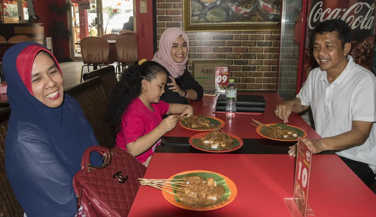 Pelatih Mitra Kukar, Jafri Sastra, didampingi istri dan kedua anaknya makan sate padang di kawasan Jakarta Selatan, Sabtu (23/1/2016). (Bola.cm/Vitalis Yogi Trisna)