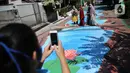 Warga berfoto di atas jalan yang telah dilukis mural di Jalan Keuangan, Cilandak, Jakarta, Rabu (26/8/2020). Museum Basoeki Abdullah bekerjasama dengan Perupa Jakarta Raya membuat mural dengan memanfaatkan ruang publik di sepanjang jalan menuju museum Basoeki Abdullah. (Liputan6.com/Faizal Fanani)