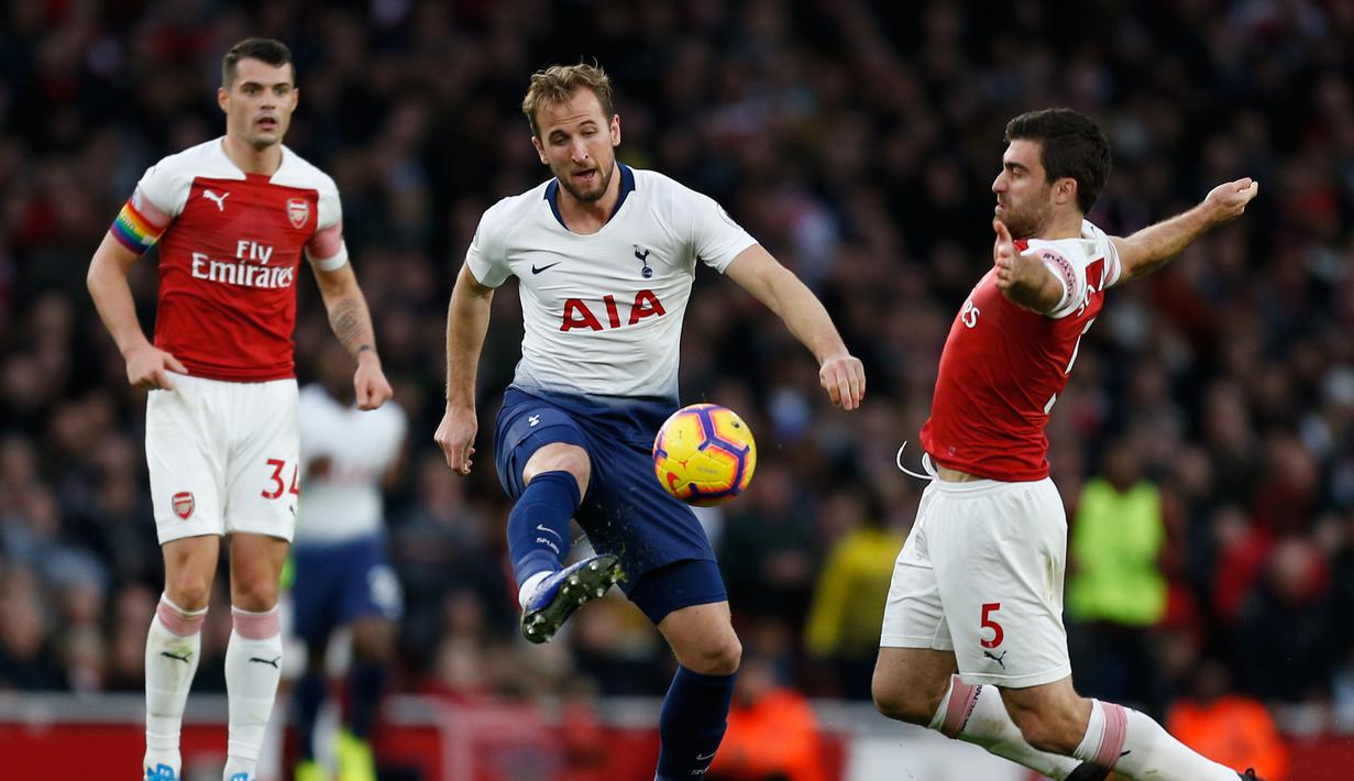 Penyerang Tottenham, Harry Kane mencoba melewati Sokratis Papasthatopaulus dalam laga lanjutan Liga Inggris pekan ke-14 yang berlangsung di stadion Emirates, London, Minggu (2/12). Tottenham Hotspur kalah 1-2 atas Arsenal. (AFP/Ian Kington)