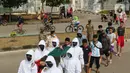 Petugas Satpol PP Kabupaten Bogor yang mengenakan pakaian hazmat menggotong warga pelanggar PSBB di kawasan Stadion Pakansari, Kabupaten Bogor, Jawa Barat, Minggu (6/9/2020). Pemkab Bogor menerapkan sanksi denda Rp 100 ribu serta sanksi sosial bagi pelanggar PSBB. (Liputan6.com/Herman Zakharia)