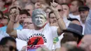 Seorang fans menggunakan topeng wajah Arsene Wegner saat laga Arsenal melawan Burnley di Emirates Stadium, London, (6/5/2018). Arsene Wegner mengumumkan mundur sebagai pelatih setelah 22 tahun bersama Arsenal. (AP/Matt Dunham)