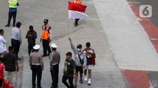 Seorang warga mengibarkan bendera merah putih saat perayaan pawai Timnas U-22 dan Juara SEA Games 2023 di kawasan Bundaran HI, Jakarta, Jumat (19/5/2023). (Liputan6.com/Herman Zakharia)