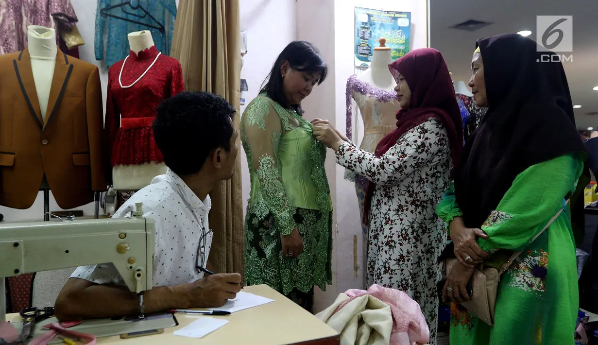 Pelanggan mencoba baju pesanannya yang dijahit di Pasar Mayestik, Jakarta Selatan, Senin (11/6). Masyarakat mulai membeli dan membuat baju pilihan mereka jelang Lebaran. (Liputan6.com/JohanTallo)