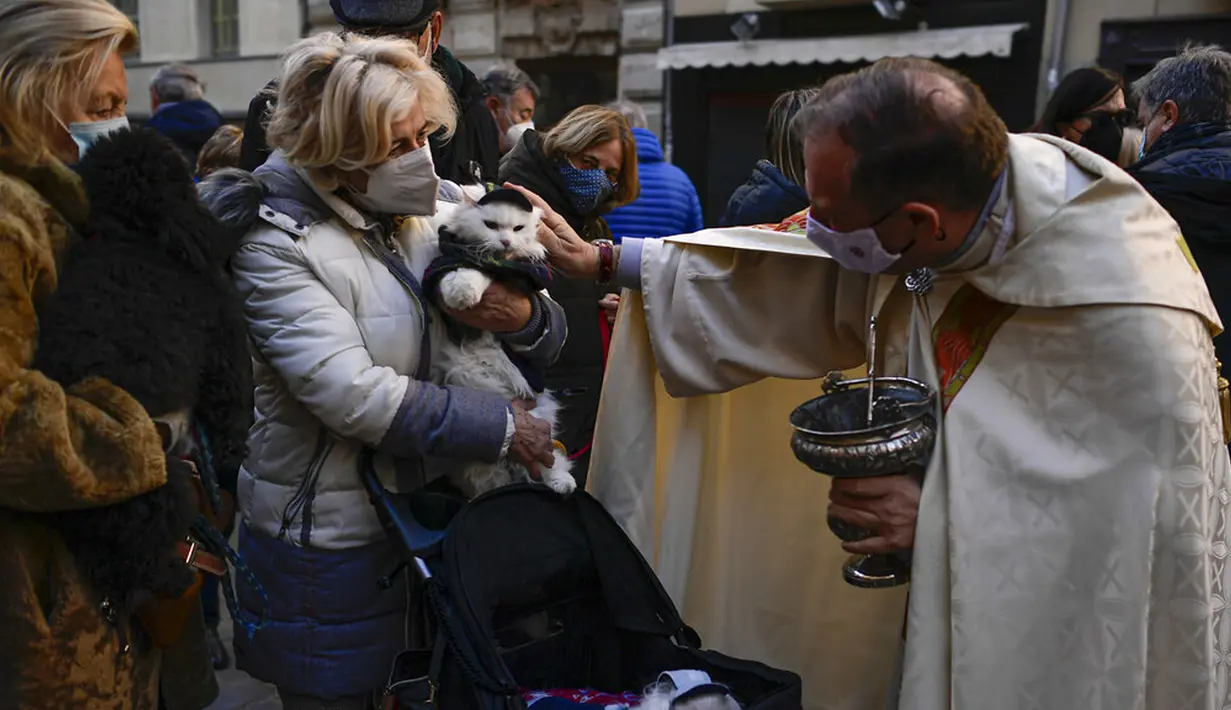 Pendeta Cesar Magana (tengah) memberkati hewan dan pemiliknya saat pesta Santo Antonius di Pamplona, Spanyol, 17 Januari 2022. Pesta santo pelindung hewan Spanyol ini dirayakan setiap tahun dan orang-orang membawa hewan peliharaan mereka ke gereja untuk diberkati. (AP Photo/Alvaro Barrientos)