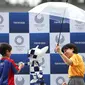 Seorang bocah berjabat tangan dengan robot maskot Olimpiade 2020, Miraitowa, pada acara hitung mundur setahun menjelang event tersebut, di Stadion Ajinomoto, Tokyo, Senin (22/7/2019). (AFP/Behrouz Mehri)