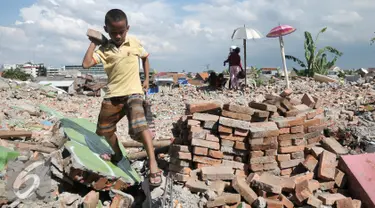 Seorang anak mengumpulkan batu bata merah dari penggusuran pemukiman Bukit Duri, Jakarta, Kamis (29/9). Sejumlah warga Bukit Duri kumpulkan batu bata merah yang utuh dari puing-puing sisa penggusuran untuk dijual kembali. (Liputan6.com/Yoppy Renato)