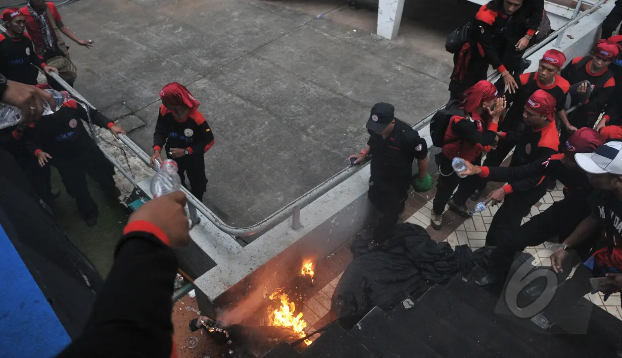 Seorang pria membakar diri dan terjun dari atap stadion Gelora Bung Karno, Jakarta, Jumat (1/5/2015). Sejumlah buruh tampak berusaha memadamkan api dengan air minum. (Liputan6.com/Herman Zakharia)