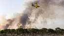 Sebuah pesawat melakukan pemadaman ke titik api yang menghanguskan hutan di dekat Mazagon, Spanyol selatan, Minggu (25/6). Sekitar 1.500 orang dievakuasi dari rumah, tempat perkemahan dan hotel menyusul kebakaran hutan tersebut. (AP Photo/Alberto Diaz)