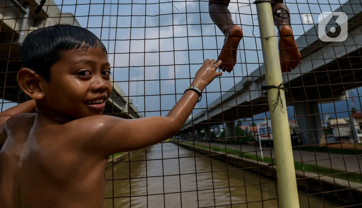 Anak-anak bermain dan berenang di aliran Kalimalang, Jakarta, Sabtu (15/2/2020). Cuaca yang tidak menentu membuat aliran air terkadang menjadi deras sehingga akan membahayakan keselamatan anak-anak saat bermain dan berenang. (merdeka.com/Imam Buhori)