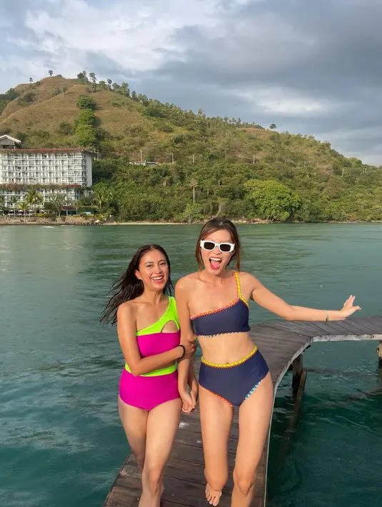 Tyna Dwi Jayanti tampil mengenakan bikini two piece model one shoulder. Tyna terlihat cantik dengan senyum ceria seperti perpaduan warna cerah bikininya, pink dan hijau neon.Penampilan Tyna berbikini selama liburan ini mendapatkan beragam pujian dari warganet. (Instagram/tynadwijayanti)