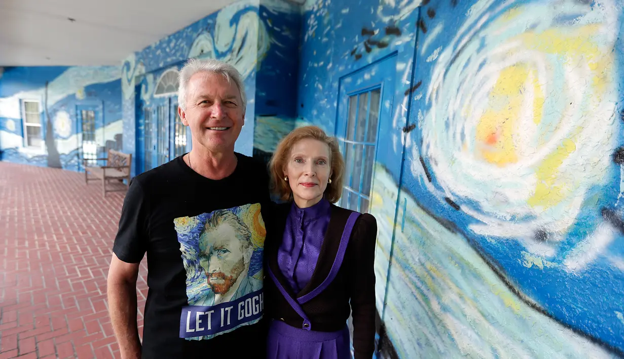Sepasang suami istri, Nancy Nemhauser dan Lubomir Jastrzebski berpose dekat mural yang menghiasi rumah mereka di Mount Dora, Florida, 18 Juli 2018. Dekorasi The Starry Night pada rumah itu dinilai melanggar aturan kota tempat tinggalnya. (AP/John Raoux)
