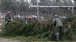 Warga memindahkan pohon tumbang akibat Topan Mujigae di Maoming, Provinsi Guangdong, China, Minggu (4/10/2015). Topan dengan kecepatan angin hingga 180 km per jam menghantam pantai selatan China dan menewaskan sedikitnya empat orang. (REUTERS/Stringer)