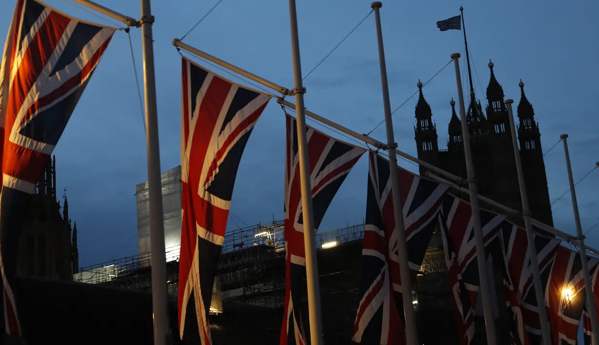 Bendera Inggris berkibar dengan latar Istana Westminster terlihat di London, Sabtu, (1/2/2020).  Mulai 1 Februari 2020 ini, Inggris secara resmi telah meninggalkan Uni Eropa (UE) setelah lebih dari tiga tahun referendum yang membuat negara itu terpecah belah. (AP Photo/Alastair Grant)