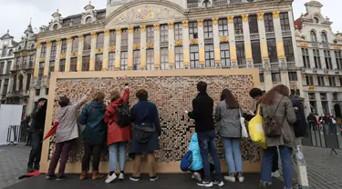 Orang-orang mengambil sejumlah balok kayu dari "The Disappearing Wall" di Grand Place, Brussel, Belgia, 3 Oktober 2020. Instalasi seni memperingati 30 tahun reunifikasi Jerman itu terdiri dari 6.000 balok kayu dilengkapi kutipan para seniman dan pemikir dari seluruh dunia. (Xinhua/Zheng Huansong)