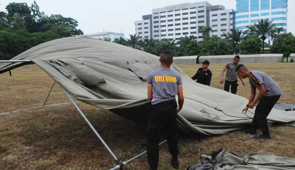 Sejumlah personel kepolisian terlihat sibuk memasang parasut tenda di halaman kompleks Gedung MPR/DPR/DPD, Senayan, Jakarta, (15/10/14). (Liputan6.com/Andrian M Tunay)