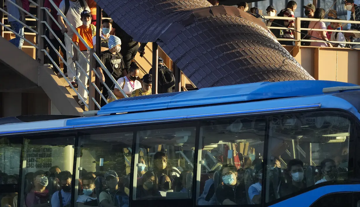 Komuter yang mengenakan masker menunggu kendaraan di halte bus di metro Manila, Filipina, Kamis (8/9/2022). Gugus Tugas Antar-Lembaga untuk Pengelolaan Penyakit Menular Filipina (IATF) menyarankan agar pemakaian masker di luar ruangan dapat dilakukan secara sukarela. (AP Photo/Aaron Favila)