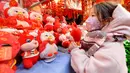 Seorang anak memilih mainan menjelang Hari Tahun Baru di sebuah pasar di Qingdao, di provinsi Shandong timur China pada 25 Desember 2022. Warga China mulai berburu pernak-pernik Tahun Baru seperti lampion, kartu tahun baru, baju, dan hiasan rumah. (AFP/STR)