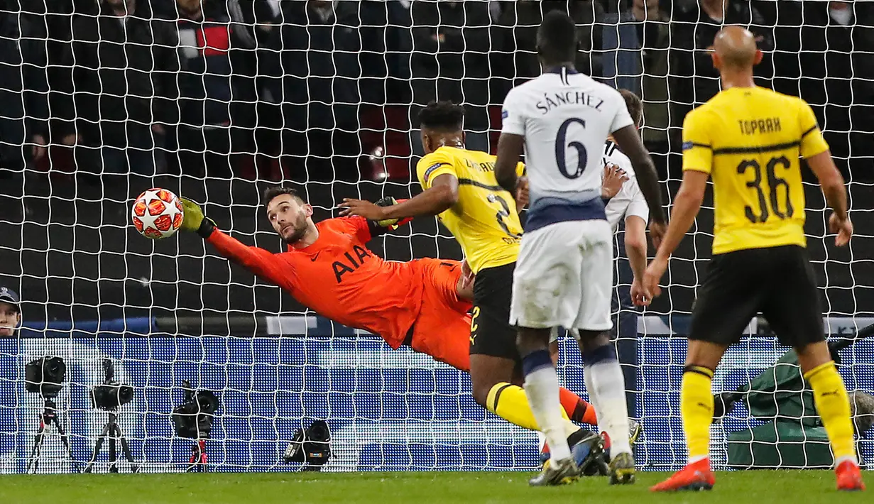 Kiper Tottenham Hotspur, Hugo Lloris menghalau bola dari sundulan bek Borussia Dortmund, Dan-Axel Zagadou pada leg pertama 16 besar Liga Champions di Stadion Wembley, Rabu (13/2). Tottenham Hotspur menang telak 3-0 atas Dortmund. (AP/ Frank Augstein)