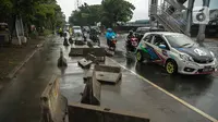 Kendaraan melintas dekat separator busway yang berserakan pascabanjir di Jalan Daan Mogot, Cengkareng, Jakarta, Jumat (3/1/2020). Separator busway tersebut berantakan akibat banjir yang menerjang sejak kemarin. (Liputan6.com/Faizal Fanani)