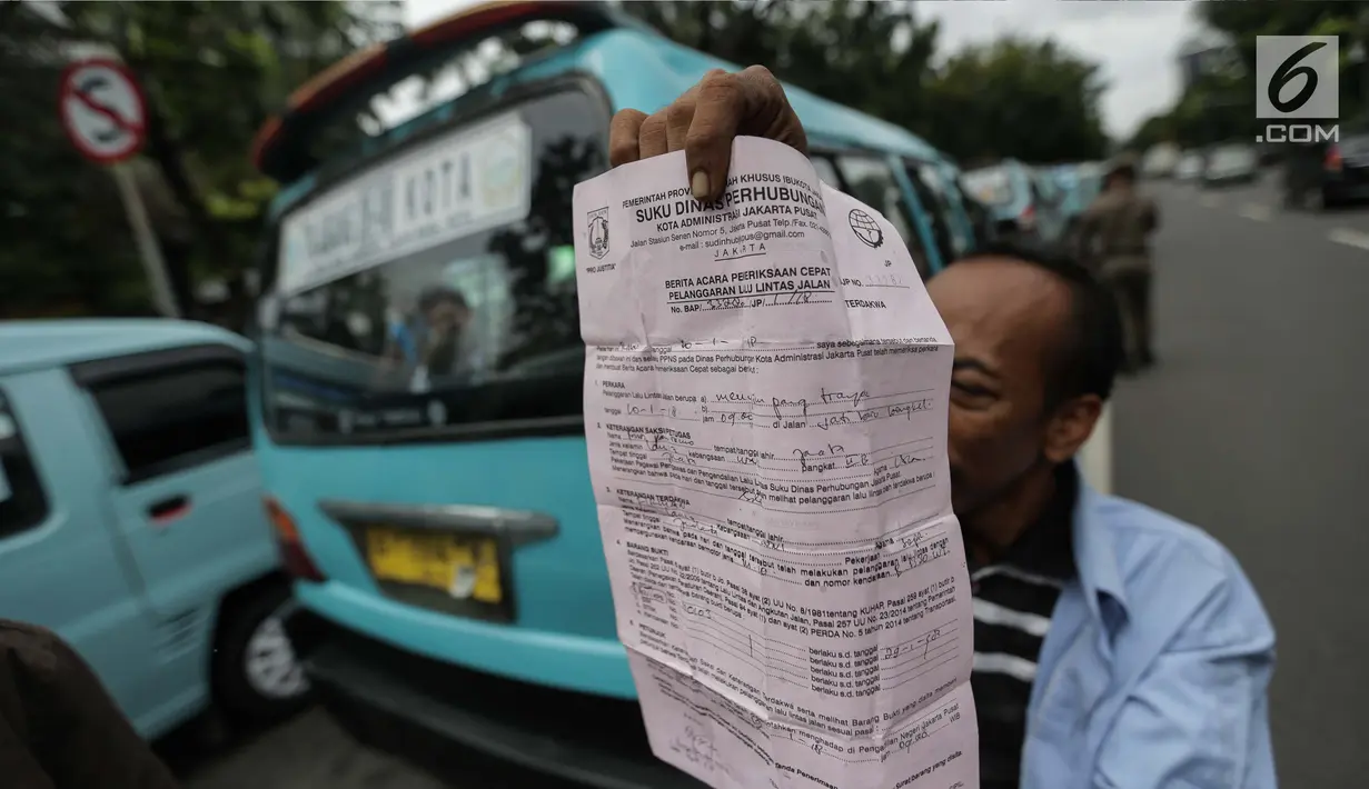 Seorang pengemudi angkutan menunjukkan surat tilang saat menggelar unjuk rasa di depan Balai Kota, Jakarta, Senin (22/1). Para sopir ini menuntut dibukanya jalan Jatibaru Raya dan putaran di depan Blok A Tanah Abang. (Liputan6.com/Faizal Fanani)