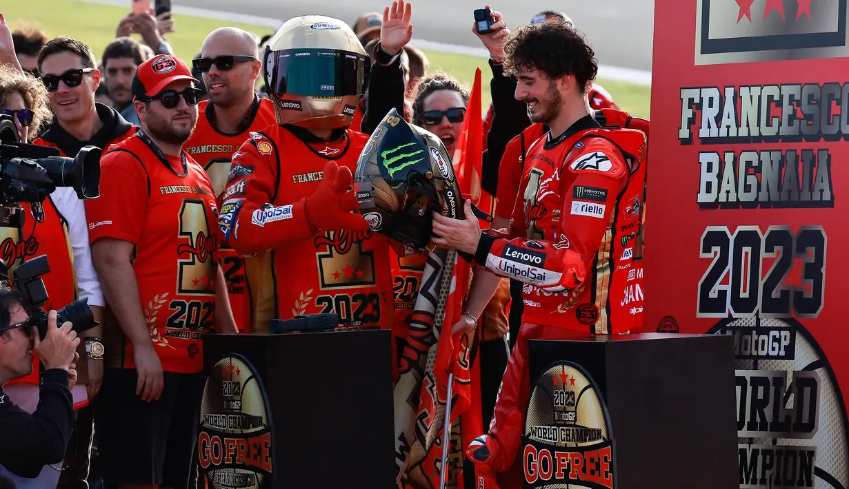 Francesco Bagnaia (kanan), merayakan keberhasilan dirinya sebagai juara dunia MotoGP 2023 setelah finis posisi pada pertama di MotoGP Valencia, Minggu (26/11/2023). (AFP/Jose Jordan)