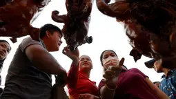 Pedagang babi panggang melayani pembeli di pasar di Phnom Penh, Kamboja (4/2). Menyambut Tahun Baru Imlek, warga Kamboja mempersiapkan daging babi panggang untuk sajian makan. (AFP Photo/Tang Chhin Sothy)