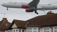 Pesawat Virgin Atlantic terbang rendah dekat atap rumah saat bersiap mendarat di Bandara Heathrow, London, 25 Oktober 2016. Perumahan yang terletak di Myrtle Avenue itu hanya sekitar 91 meter dari landasan Bandara Heathrow. (AP Photo / Frank Augstein)