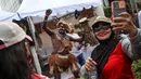 Warga berswafoto dengan suku dari Papua yang sedang menabuh gendang saat mengkampanyekan Sail Teluk Cenderawasih bertepatan dengan Hari Bebas Kendaraan Bermotor (HBKB), Kawasan Thamrin, Jakarta, Minggu (8/10/2023). (Liputan6.com/Angga Yuniar)