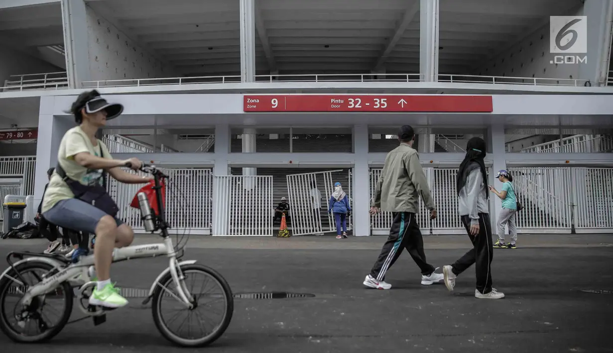 Warga berolahraga melintasi pintu masuk zona 9 Stadion Utama Gelora Bung Karno yang rusak pada Final Piala Presiden 2018, Jakarta, Minggu (18/2). Kerusakan disebabkan suporter salah satu tim sepakbola yang merangsek masuk. (Liputan6.com/Faizal Fanani)