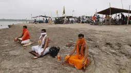 Umat Hindu menutup wajah mereka dengan kain untuk mencegah terpapar virus corona COVID-19 saat melakukan ritual selama gerhana matahari di pertemuan Sungai Gangga dan Sungai Yamuna di Sangam, Prayagraj, India, Minggu (21/6/2020). (AP Photo/Rajesh Kumar Singh)